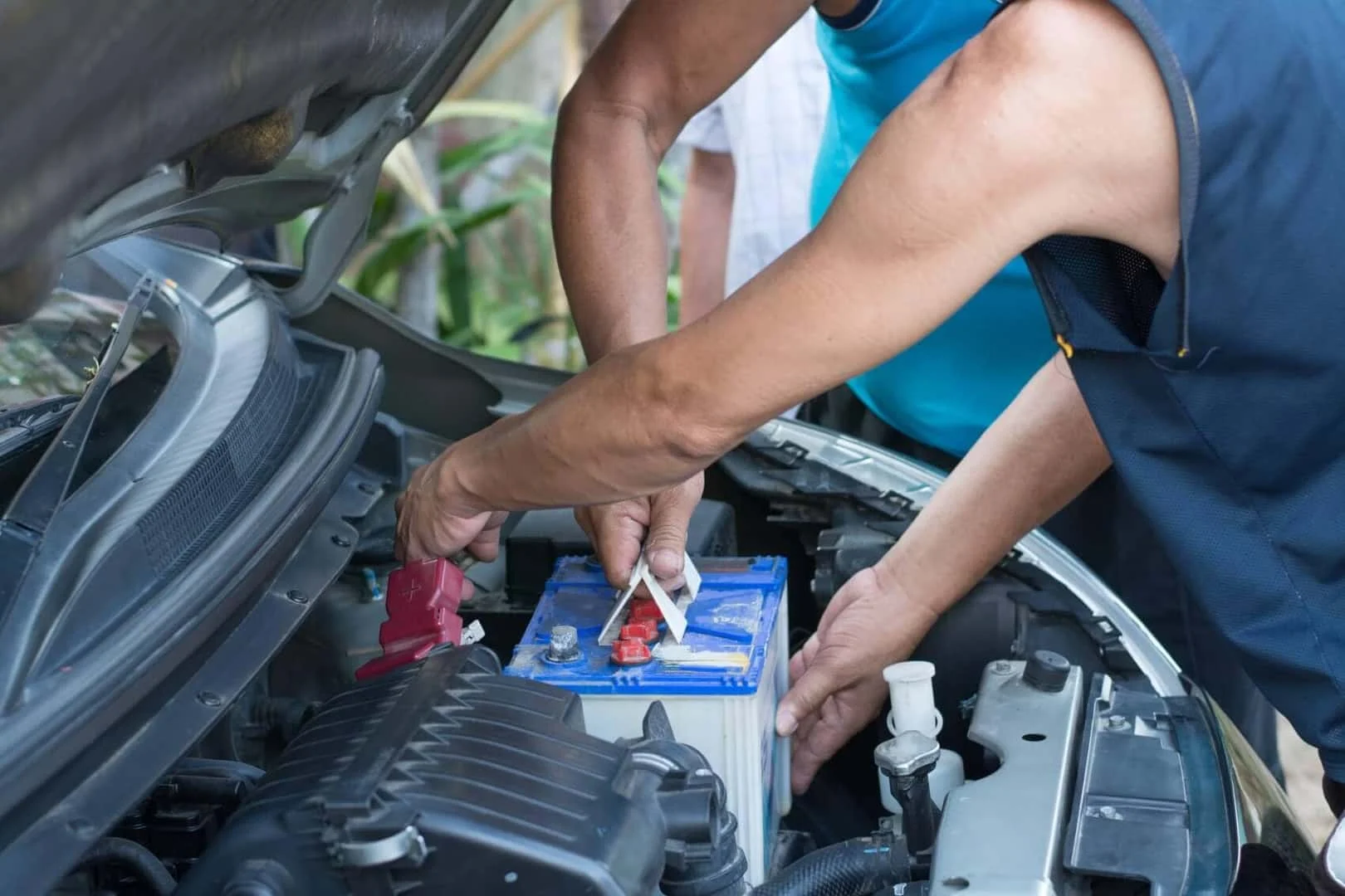 Technician checking a car battery under the hood