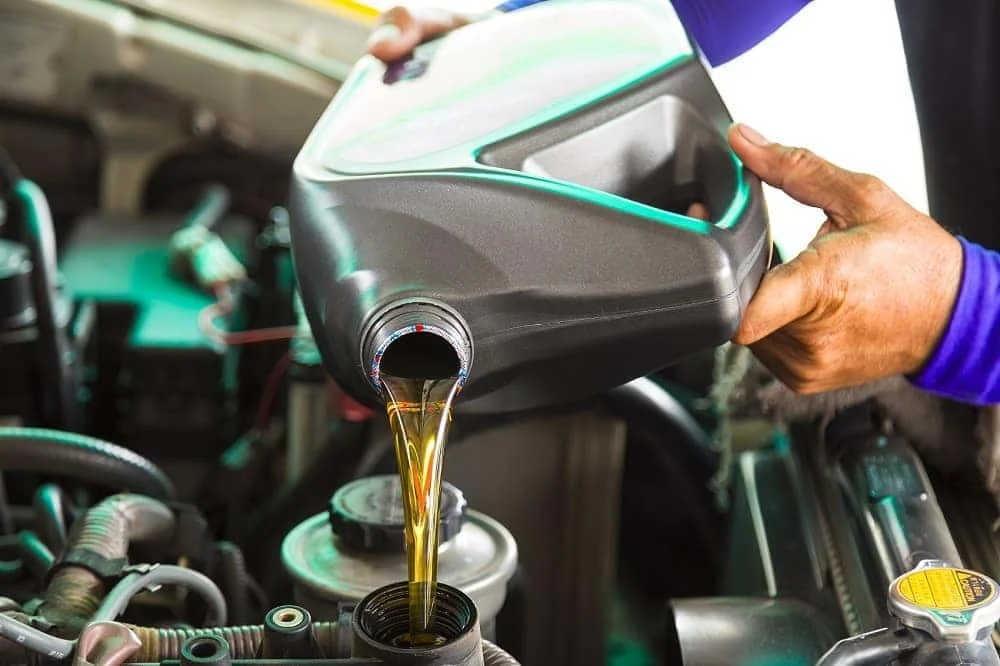 Technician pouring new engine oil into a BMW
