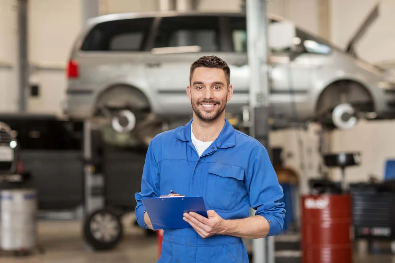 BMW service technician with clipboard in front of a lifted vehicle