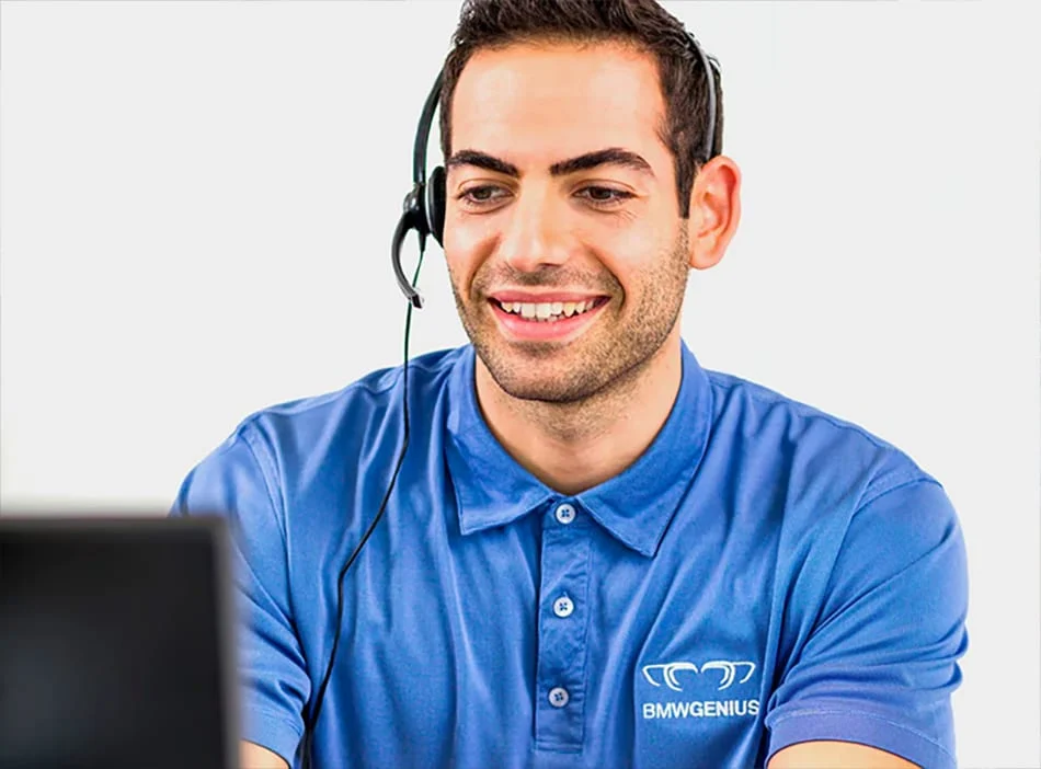 A BMW Genius worker on a headset looking at a computer